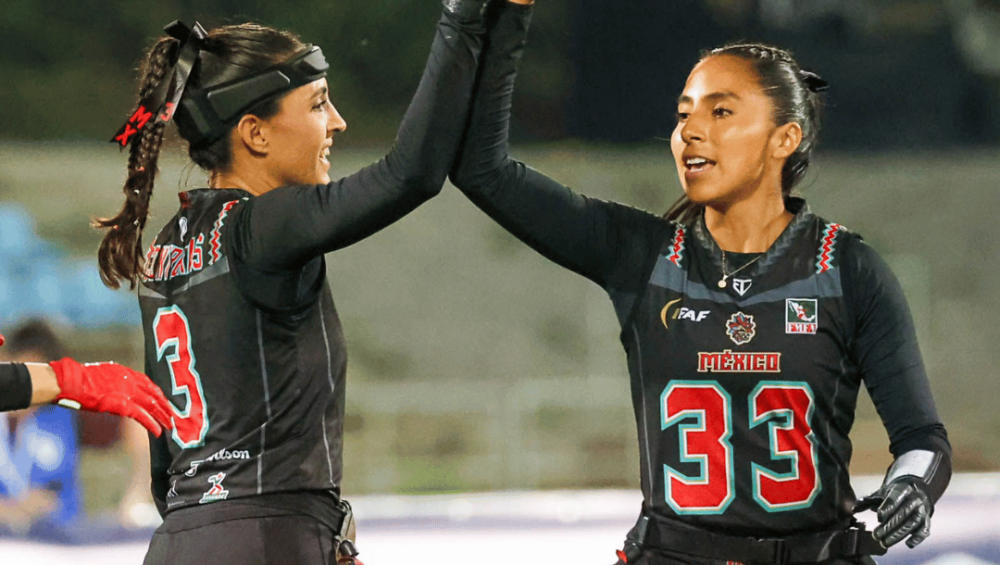 Two female flag footballers celebrate during a game