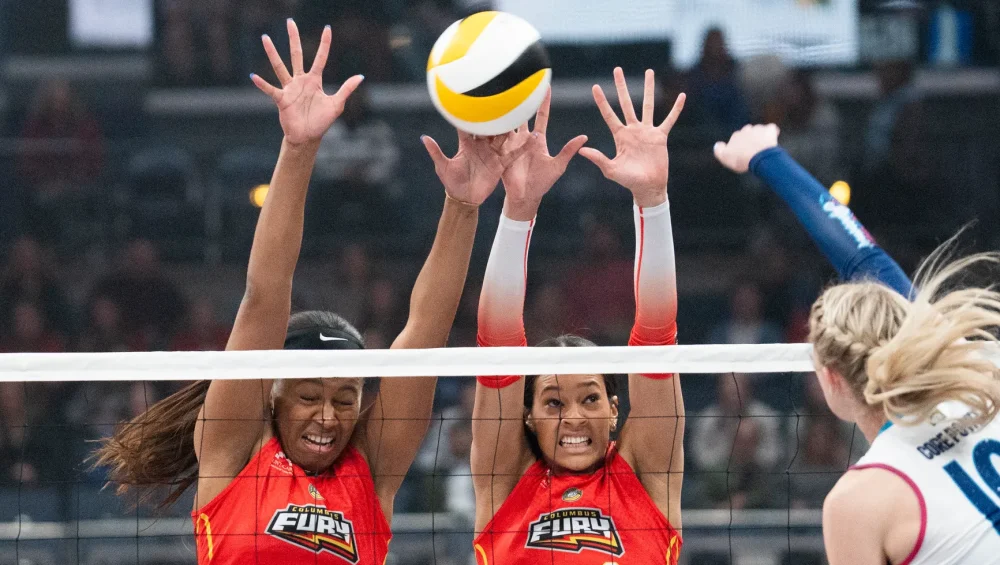 Columbus Fury players blocking a ball in a volleyball match